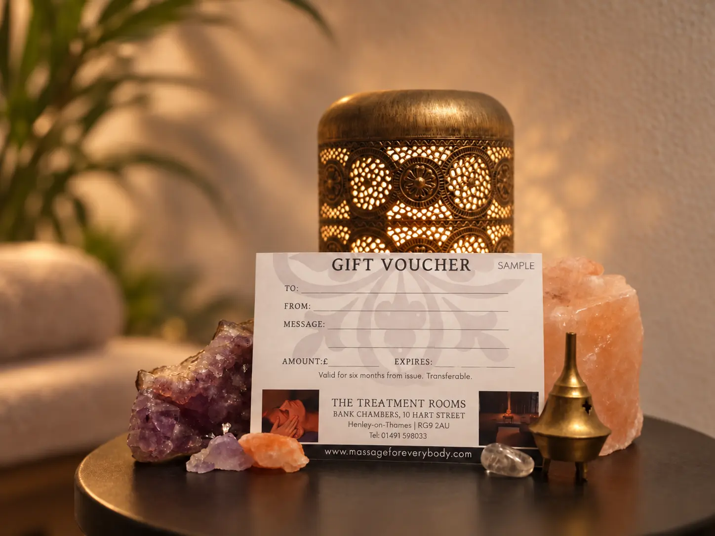 Example of a Treatment Rooms printed gift voucher beside a lamp and crystals